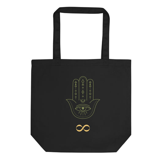Econscious EC8000 brand eco tote. Black, 16x14 ½ inches, 100 percent certified organic cotton eco tote bag. Front of bag has yellow infinity symbol (infinity sign) and green hamsa hand (hand of Fatima) brand logo. JAMILLIAH'S WISDOM IS TIMELESS SHOP - wisdomistimeless.com.