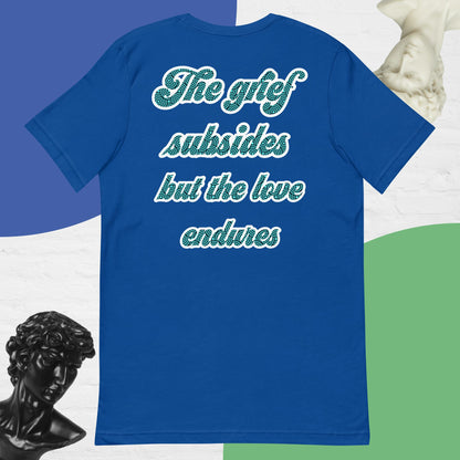 Bella + Canvas 3001 t-shirt. True royal blue colored, back view. White, green, and black scripted written quote "The grief subsides but the love endures." Shown laying flat on a white, green, and blue background with black and white bust sculptures of people's head and necks. Jamilliah's Wisdom Is Timeless Shop - wisdomistimeless.com.