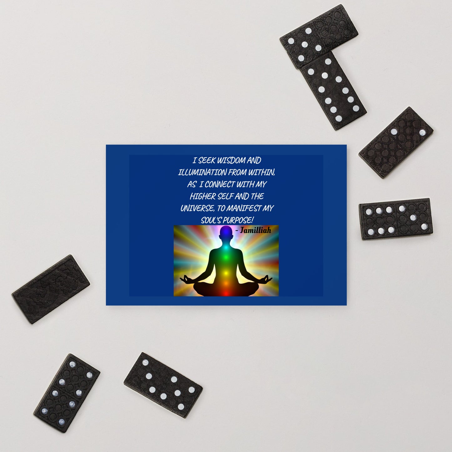 Postcard designed with zen image of a being in lotus pose, having balanced chakras, surrounded by rainbow light aura. Original wise quote mantra. "I Seek Wisdom And Illumination From Within, As I Connect With My Higher Self And The Universe, To Manifest My Soul's Purpose!" - Jamilliah. Postcard shown with dominoes. JAMILLIAH'S WISDOM IS TIMELESS SHOP - wisdomistimeless.com.