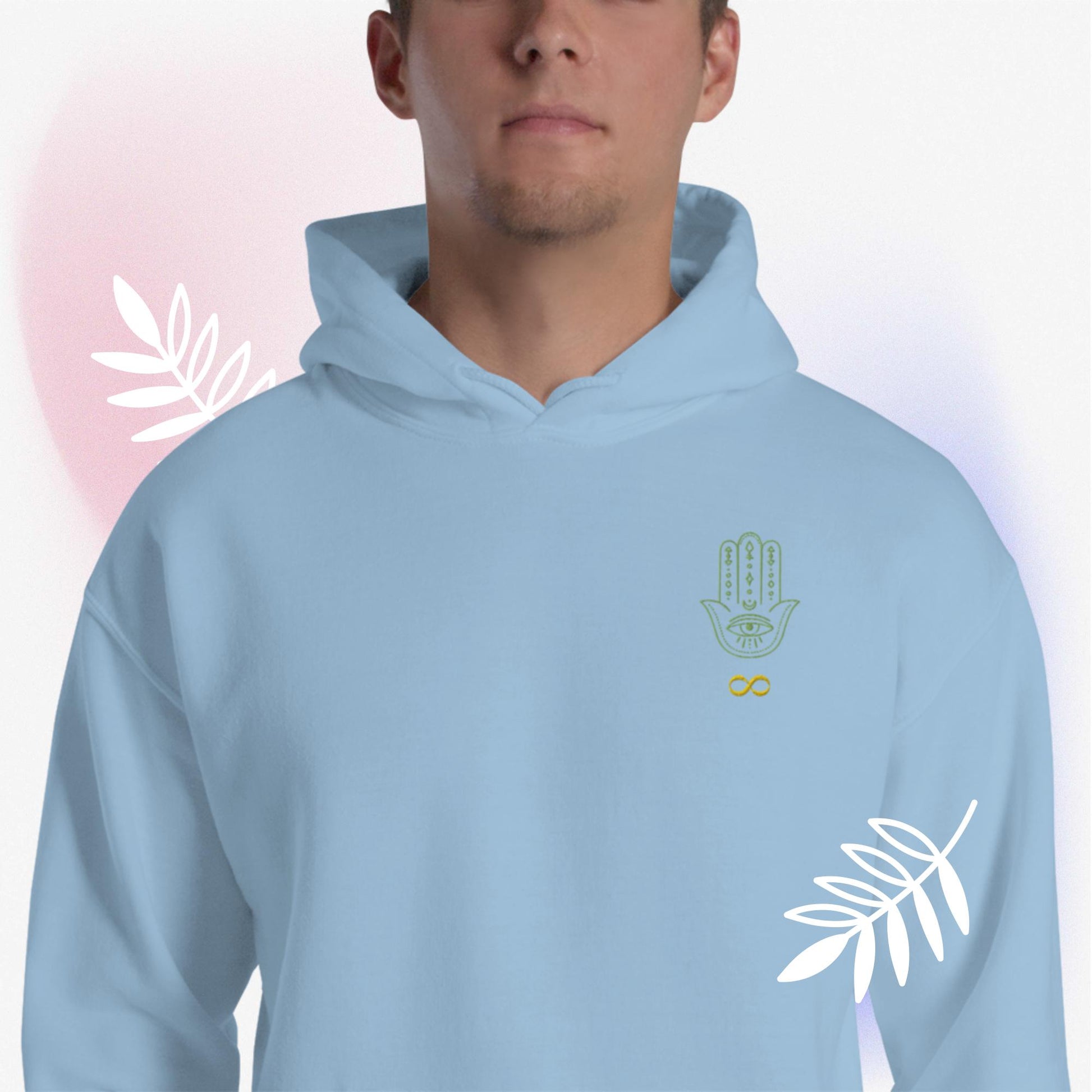 Gildan 18500, designer brand, unisex, heavy blend, hoodie. Front of hoodie has JAMILLIAH'S WISDOM IS TIMELESS SHOP's brand logo of a hamsa hand and infinity symbol. Worn by male model, surrounded by white leaves, and pink hue. JAMILLIAH'S WISDOM IS TIMELESS SHOP - wisdomistimeless.com.