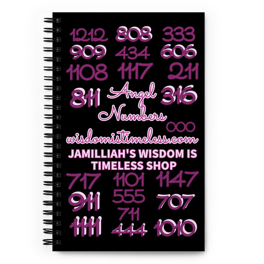Wire-o spiral notebook journal. Black cover with purple and purple/pink angel numbers, front view. Angel numbers 811, 444, 1111, 555, 1010, 808, 1212, 711, 316, 000, 333, 911, 909, 434, 606, 1108, 1117, 211, 717, 1101, 1147, and 707. 5.5 inches x 8.5 inches. 140 dotted pages with soft flexible covers. Shown on white background. Jamilliah's Wisdom Is Timeless Shop - wisdomistimeless.com.