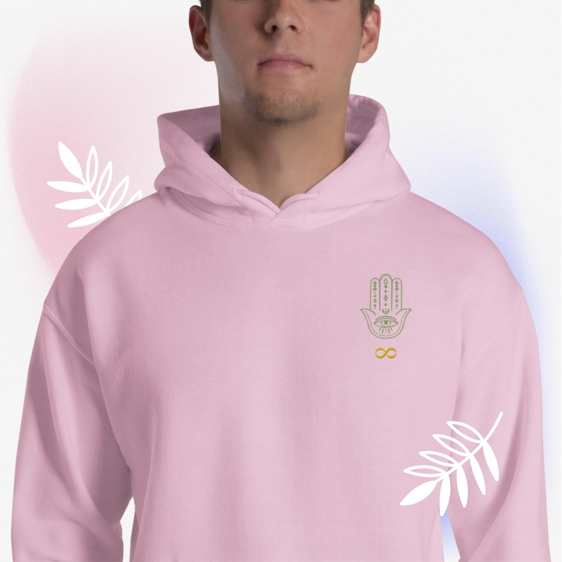 Light pink, unisex, heavy blend, hoodie, front. Embroidered, otherworldly, supernatural, hamsa hand/infinity symbol logo. Worn by male model, surrounded by white leaves, and pink and blue hues. JAMILLIAH'S WISDOM IS TIMELESS SHOP - wisdomistimeless.com.