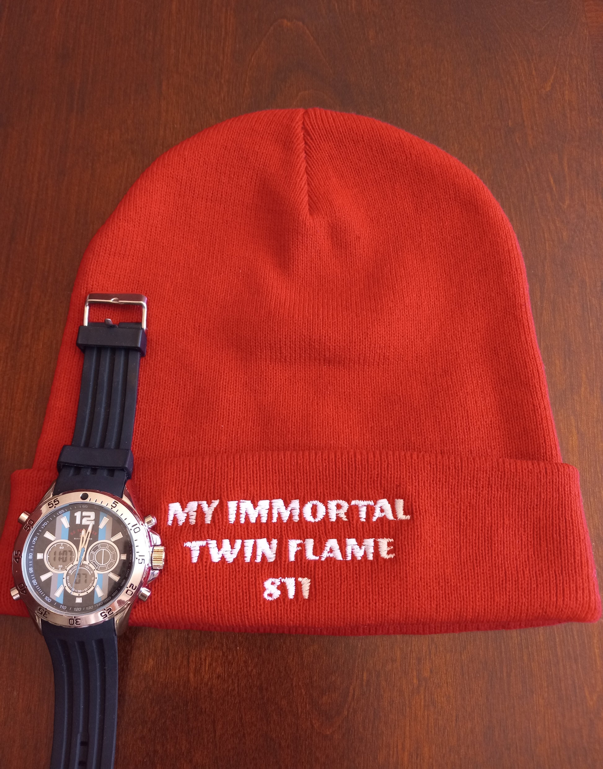 Red and white knit beanie with original tagline. "My Immortal Twin Flame 811." Shown with a watch. JAMILLIAH'S WISDOM IS TIMELESS SHOP - wisdomistimeless.com.